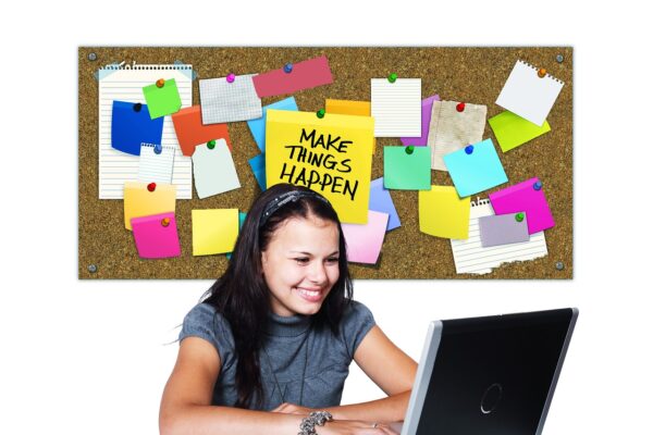 Visionboard met kleurrijke post-its en notities, terwijl een glimlachend meisje aan tafel werkt op een laptop, symbool voor het creëren van een inspirerende toekomst en groei. | Vision board with colorful post-its and notes, with a smiling girl at the table working on her laptop, symbolizing creating an inspiring future and growth.