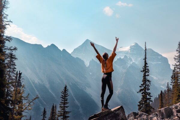 Vrouw op een bergtop die haar kracht en visie omarmt. | Woman on a mountain embracing her strength and vision.