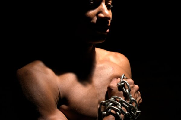 Man holding chains, symbol of breaking free from limitations. | Man die kettingen vasthoudt, symbool voor het doorbreken van blokkades.